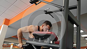 Young muscular man during training in the gym performs pushups on the bars