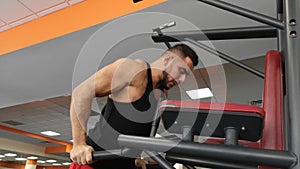 Young muscular man during training in the gym performs pushups on the bars