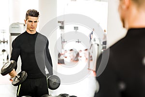 Young muscular man working out in a gym and lifting weights