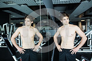 Young muscular man workout in gym near the mirror shadows