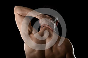 Young muscular sport man holding sore neck massaging cervical area suffering body pain