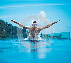 Young, muscular swimmer splashing water