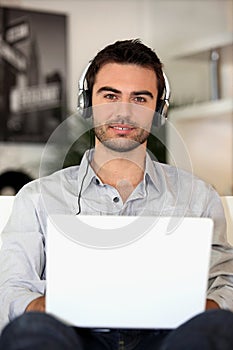 Young music lover with earphones and laptop