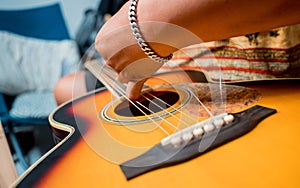 Young musician changing strings on a classical guitar in a guitar shop