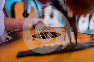 Young musician changing strings on a classical guitar in a guitar shop