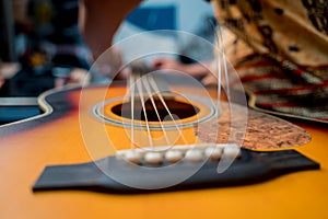 Young musician changing strings on a classical guitar in a guitar shop