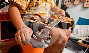 Young musician changing strings on a classical guitar in a guitar shop