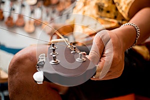 Young musician changing strings on a classical guitar in a guitar shop