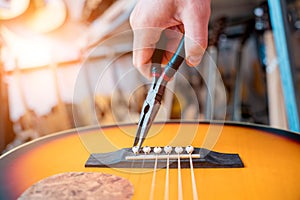 Young musician changing strings on a classical guitar in a guitar shop