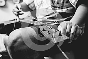 Young musician changing strings on a classical guitar in a guitar shop