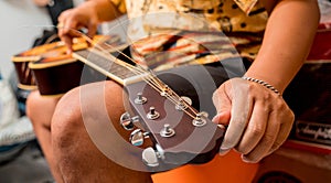 Young musician changing strings on a classical guitar in a guitar shop