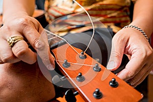 Young musician changing strings on a classical guitar in a guitar shop