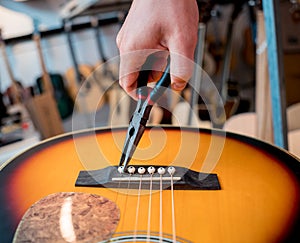 Young musician changing strings on a classical guitar in a guitar shop