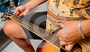 Young musician changing strings on a classical guitar in a guitar shop