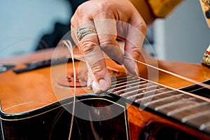 Young musician changing strings on a classical guitar in a guitar shop