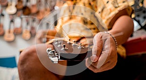 Young musician changing strings on a classical guitar in a guitar shop