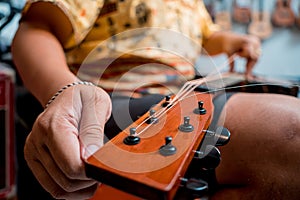 Young musician changing strings on a classical guitar in a guitar shop