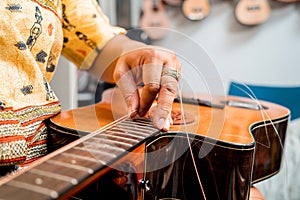 Young musician changing strings on a classical guitar in a guitar shop