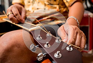 Young musician changing strings on a classical guitar in a guitar shop