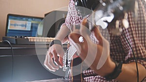 Young musician composes and records music playing the electric guitar using computer and keyboard