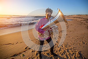 Young musician play the trumpet on rocky sea coast during surf.