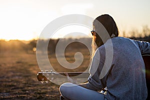 Young musician playing acoustic guitar at dusk