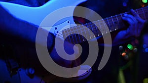 Young Musician playing electric guitar on festival with band under the stage lights. Male singer and guitarist playing guitar at l