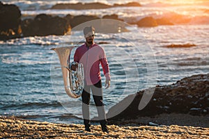 Young musician playing the trumpet on the sea coast.