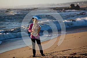 Young lone musician playing the tuba on the sea coast