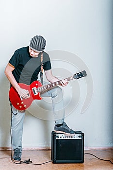 Young musician with red guitar isolated on white. Rockstar man playing electric guitar. Guy with a guitar combo