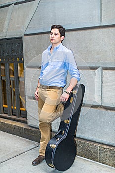 Young musician is standing on the street, relaxing, thinking