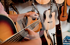 Young musician tuning a classical guitar in a guitar shop