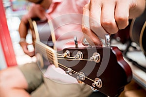 Young musician tuning a classical guitar in a guitar shop