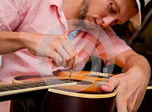 Young musician tuning a classical guitar in a guitar shop