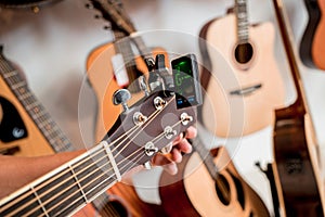 Young musician tuning a classical guitar in a guitar shop