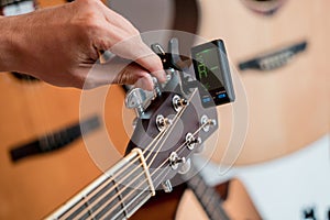 Young musician tuning a classical guitar in a guitar shop