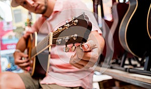 Young musician tuning a classical guitar in a guitar shop