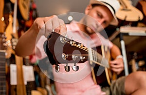 Young musician tuning a classical guitar in a guitar shop