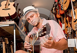 Young musician tuning a classical guitar in a guitar shop