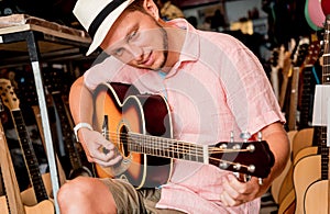 Young musician tuning a classical guitar in a guitar shop