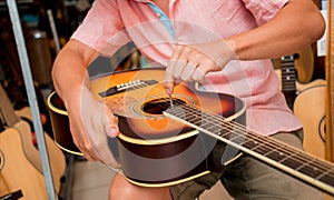 Young musician tuning a classical guitar in a guitar shop