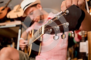 Young musician tuning a classical guitar in a guitar shop