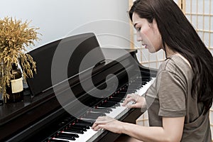 Young musician woman playing piano in living room