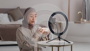 Young muslim asian woman blogger recording video about new pampering cream, telling about smell and consistency