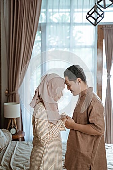 Young Muslim couple smiling at each other forehead facing each other and holding hands