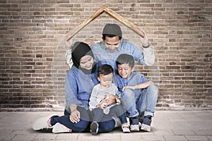 Young Muslim family plays under a roof symbol