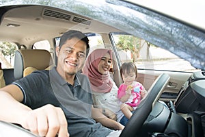 Young muslim family , transport, leisure, road trip and people concept - happy man, woman and little girl traveling in a car