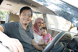 Young muslim family , transport, leisure, road trip and people concept - happy man, woman and little girl traveling inside a car