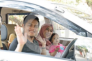 Young muslim family , transport, leisure, road trip and people concept - happy man, woman and little girl waving at camera ready