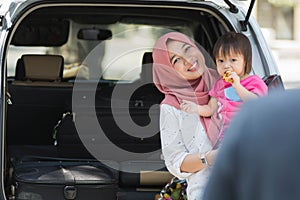 Young muslim family , transport, leisure, road trip and people concept - happy woman and little girl smilling at father to say